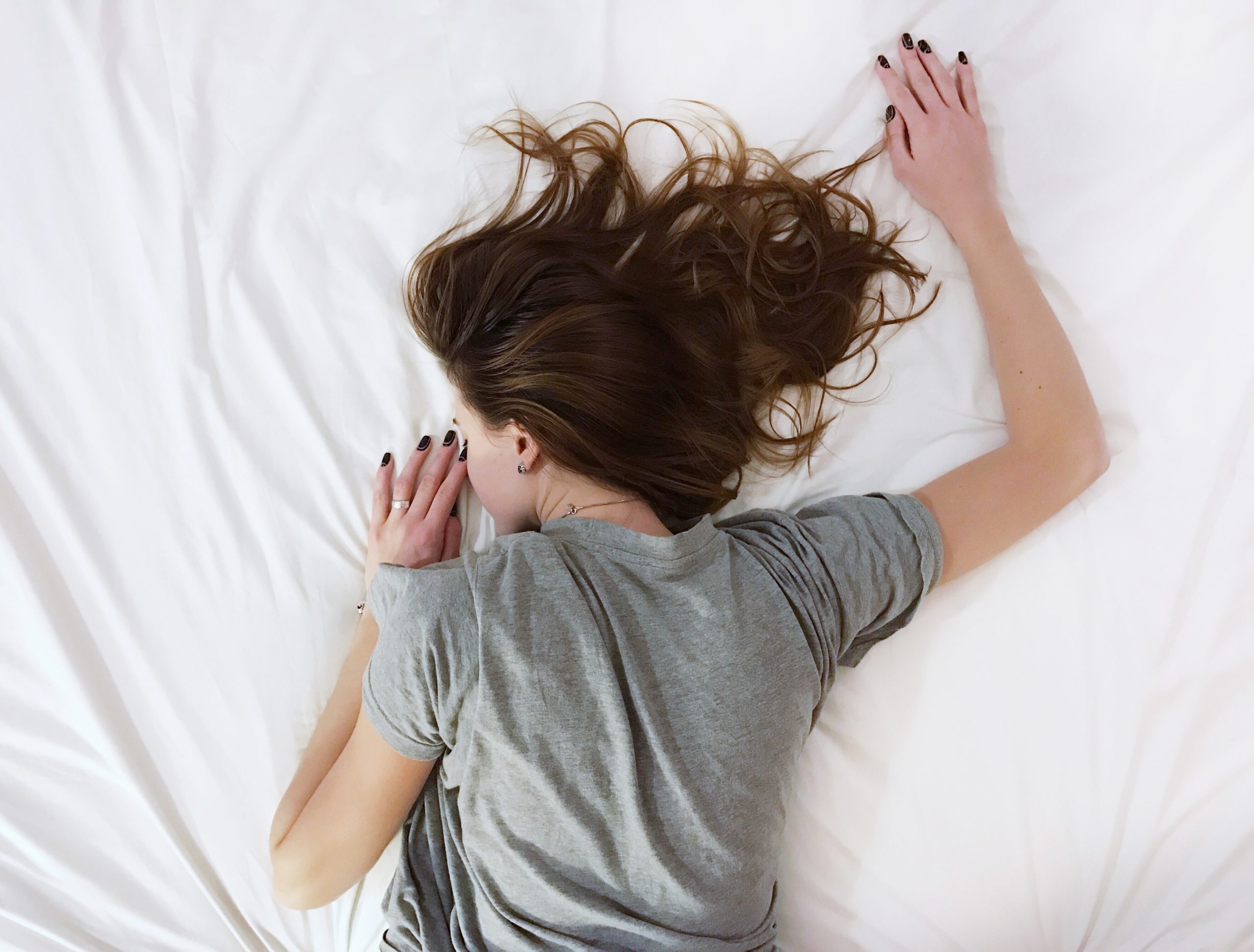 woman lying face down on white sheets