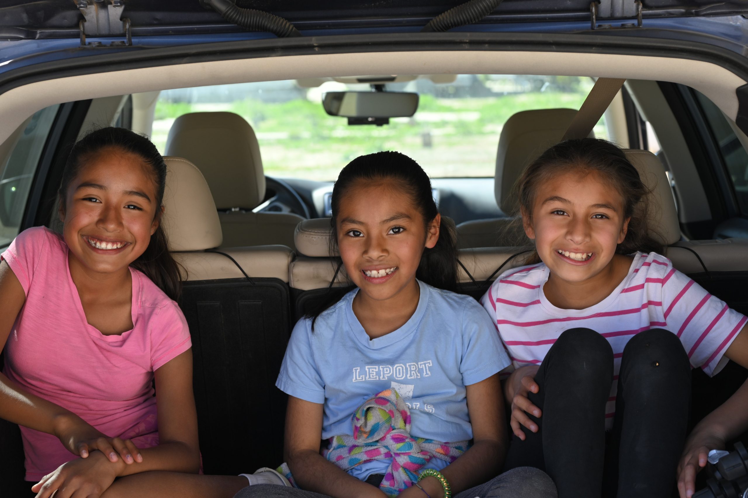 young girls sitting in the boot of a car