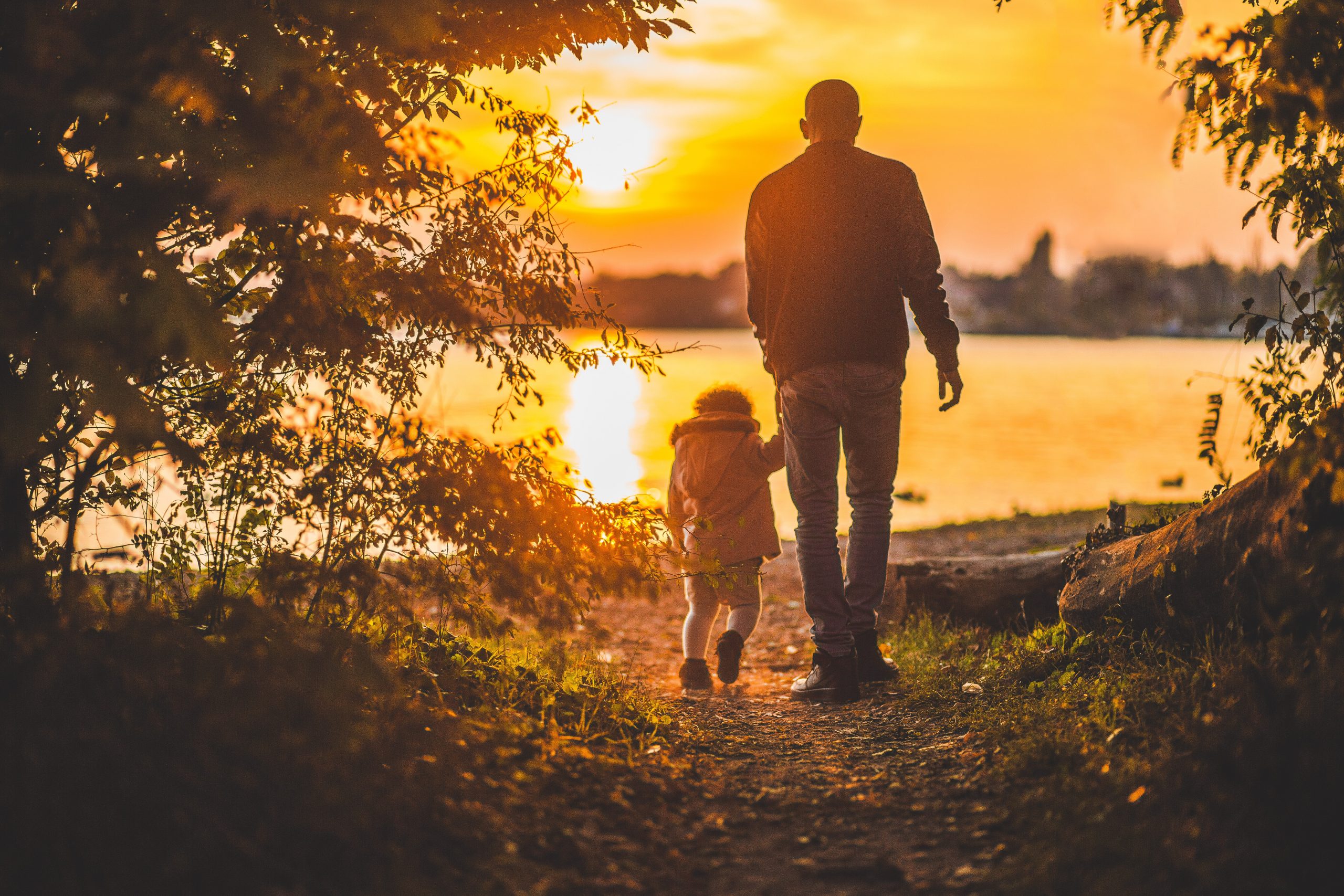 people walking towards water in sunset