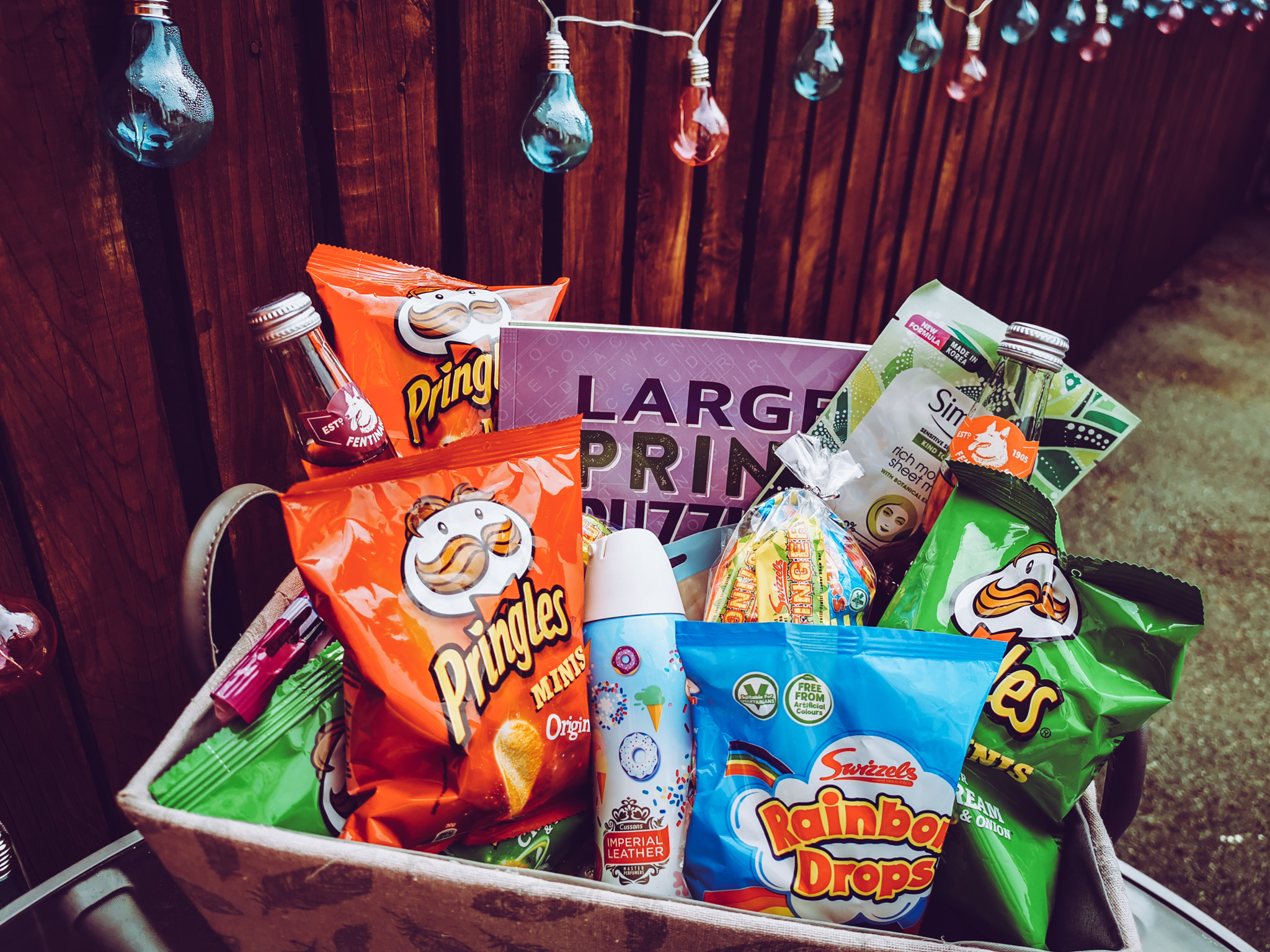 a hamper of sweets crisps and gifts with decorative lights in the background