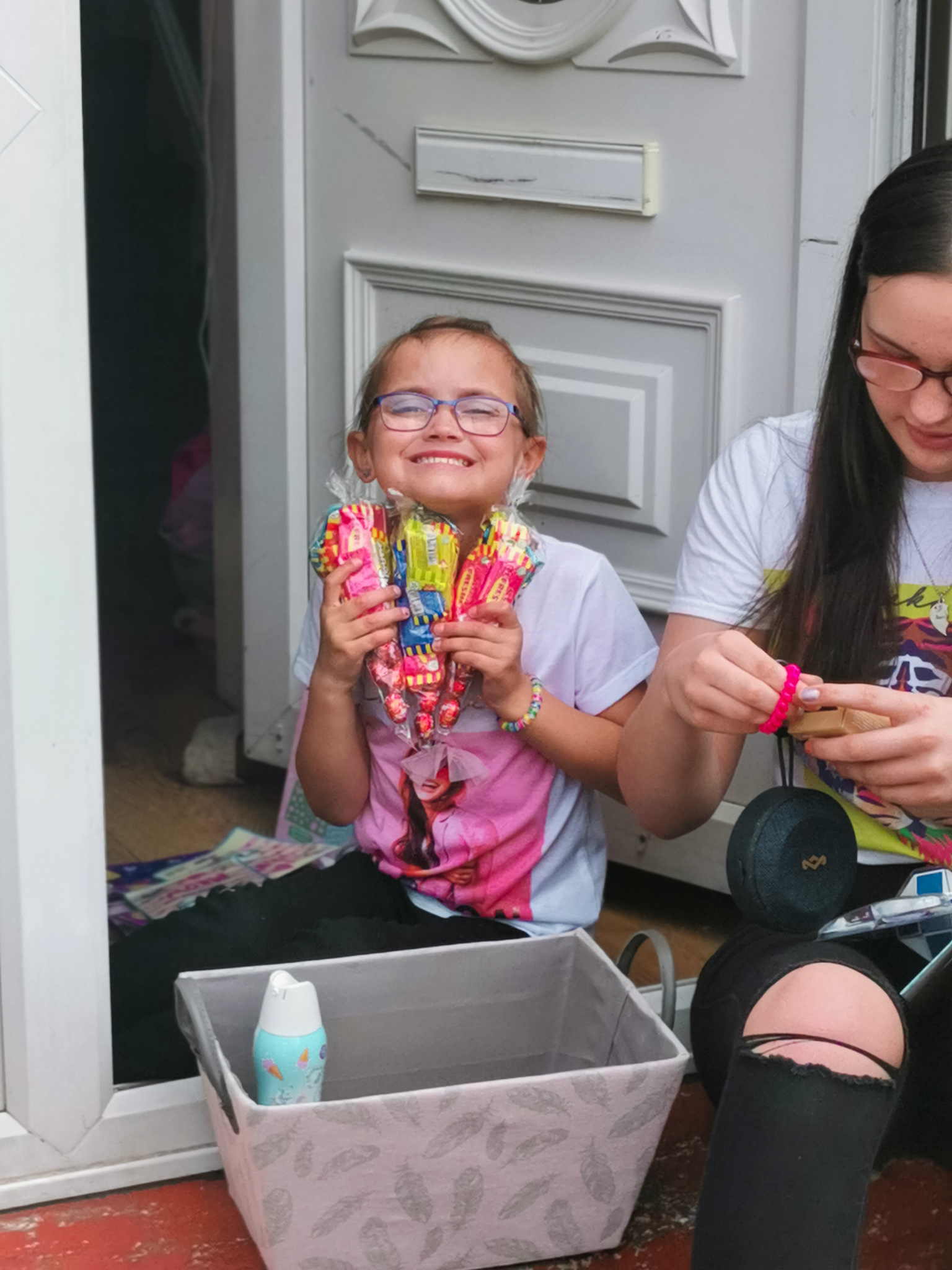young girl grinning hlding tubes of swizzels sweets
