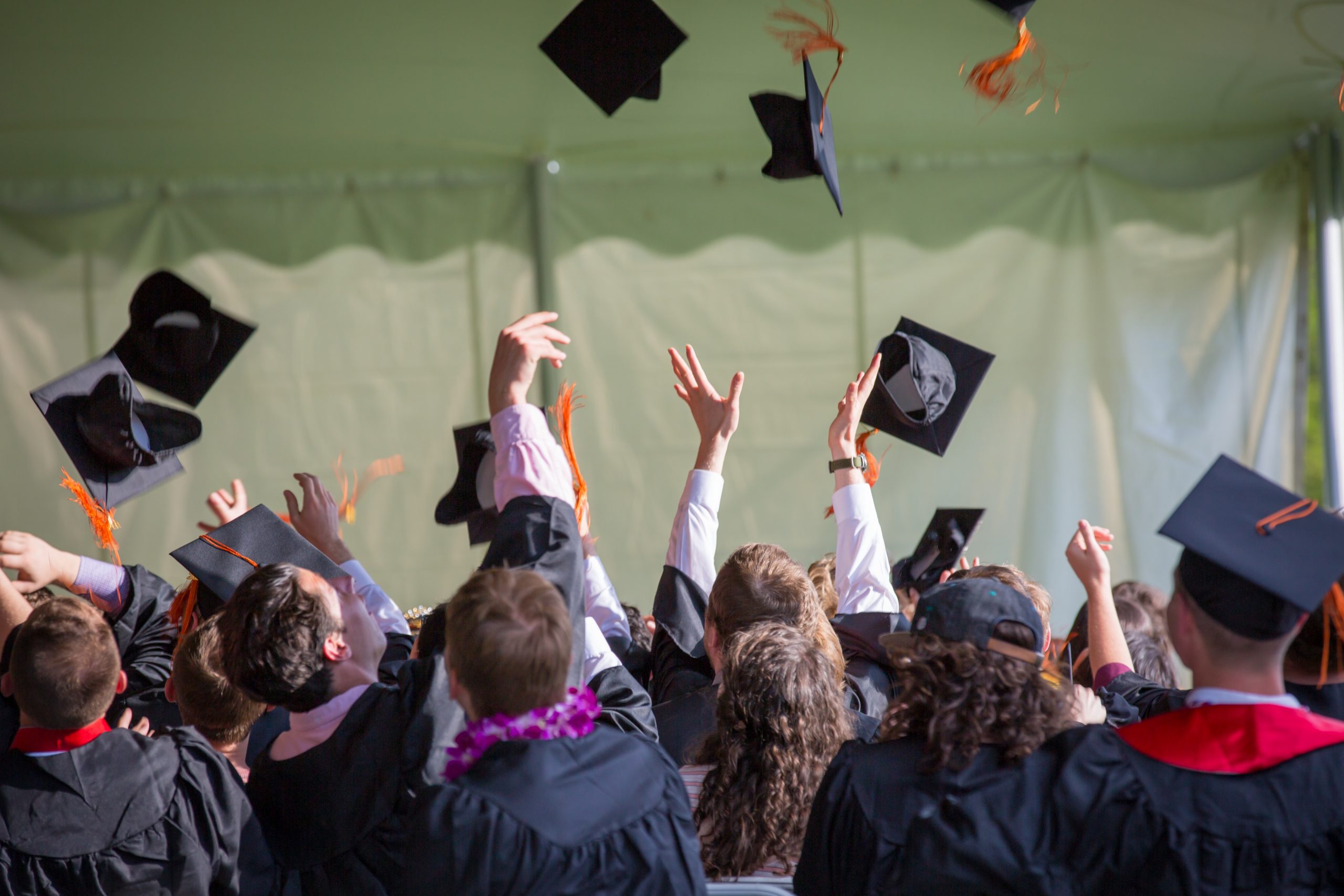 people graduation throwing caps into the air