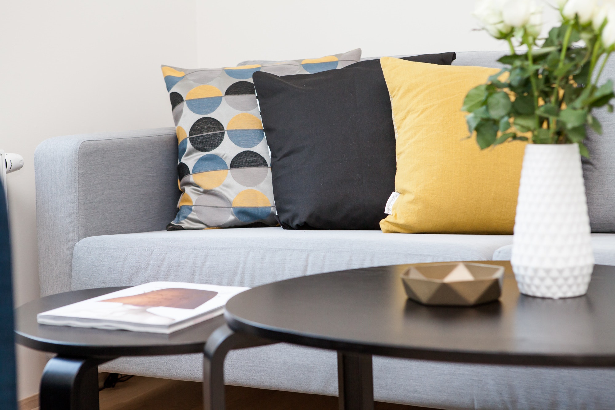 close up of a coffee table and sofa with yellow and grey cushions