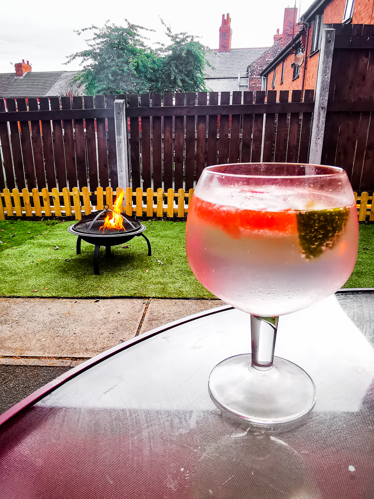 glass of vodka and lemonade in a garden setting with firepit in background