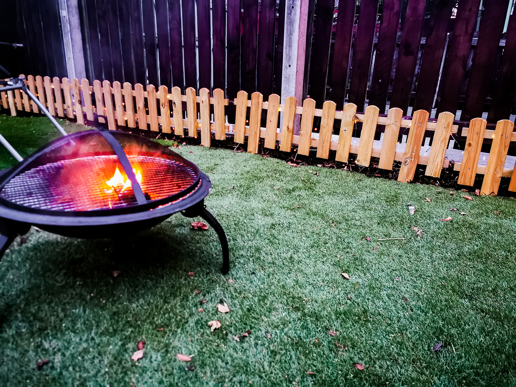dusk view of a fire pit and small picket fence