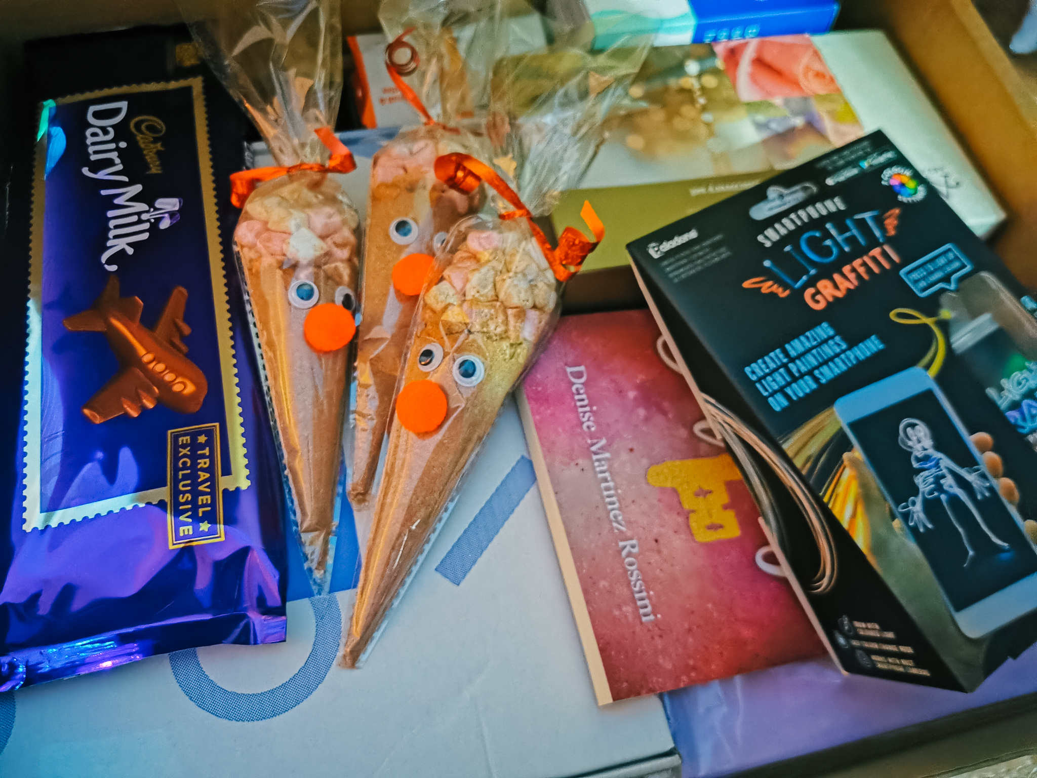 close up of a hamper box containing hot chocolate cones books and gifts.