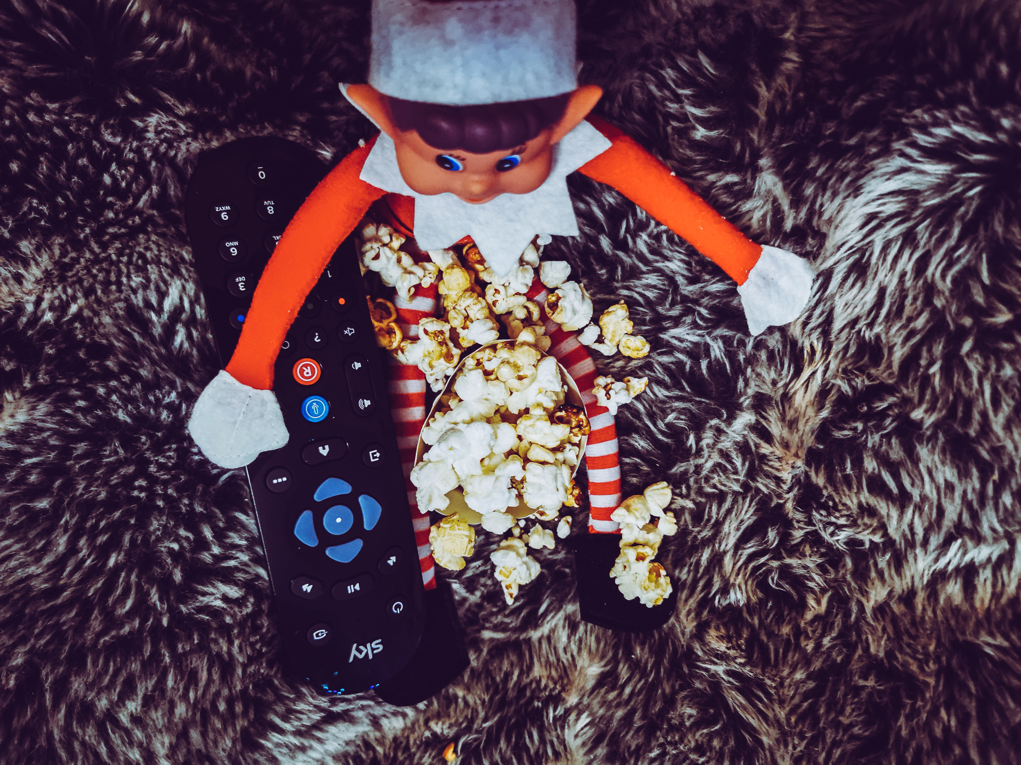 an elf on a grey cushion surrounded by popcorn
