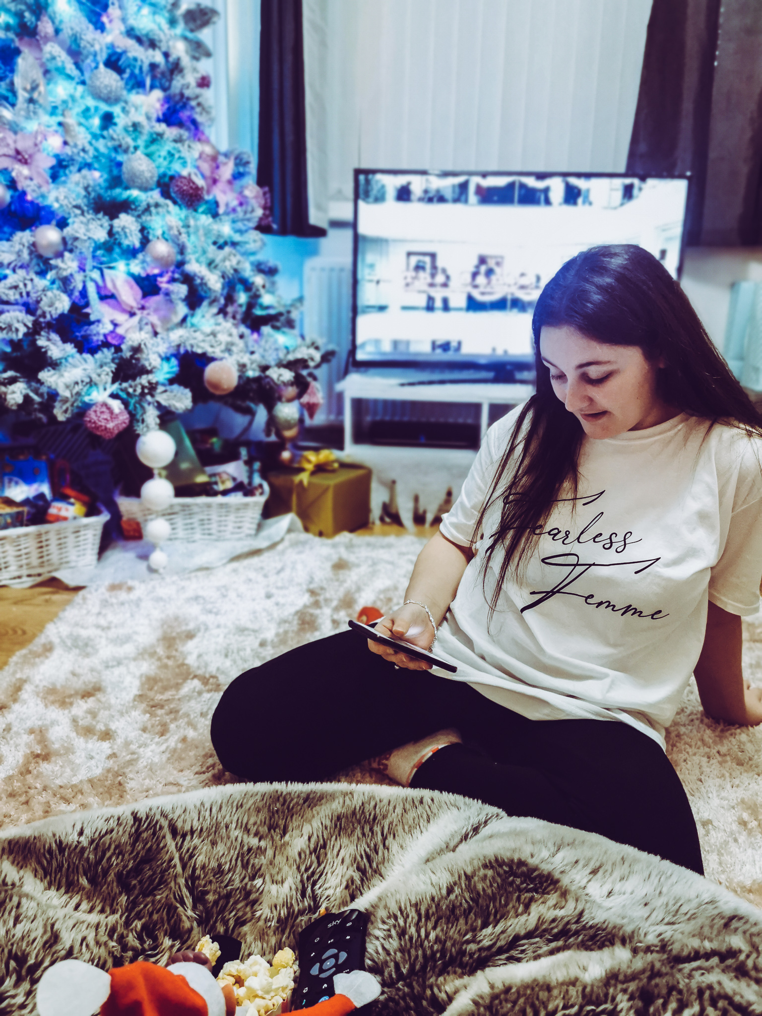 girl wearing a white tshirt and leggings sat on a pink rug in a festive room