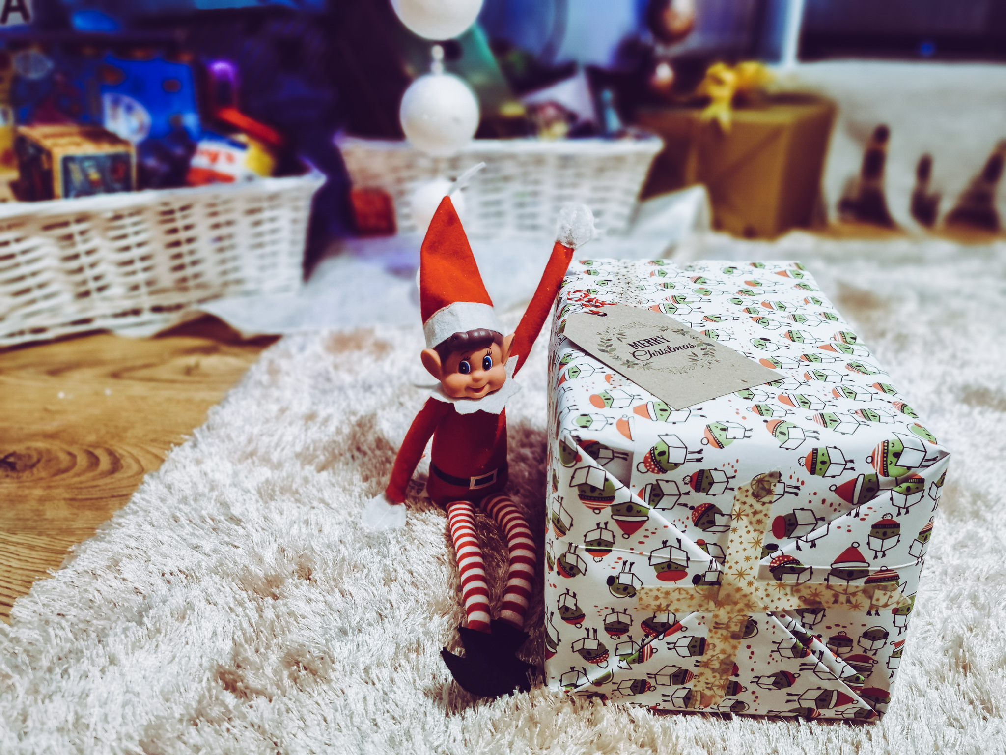 an elf on the shelf next to a gift wrapped box