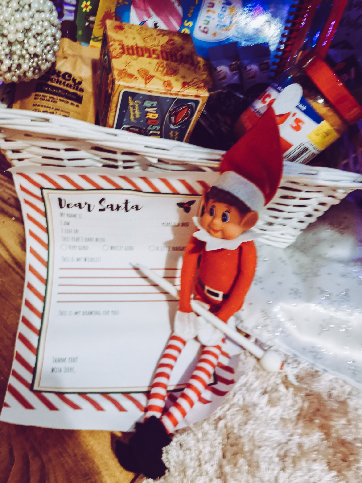 an elf sat in front of a basket with a letter for santa