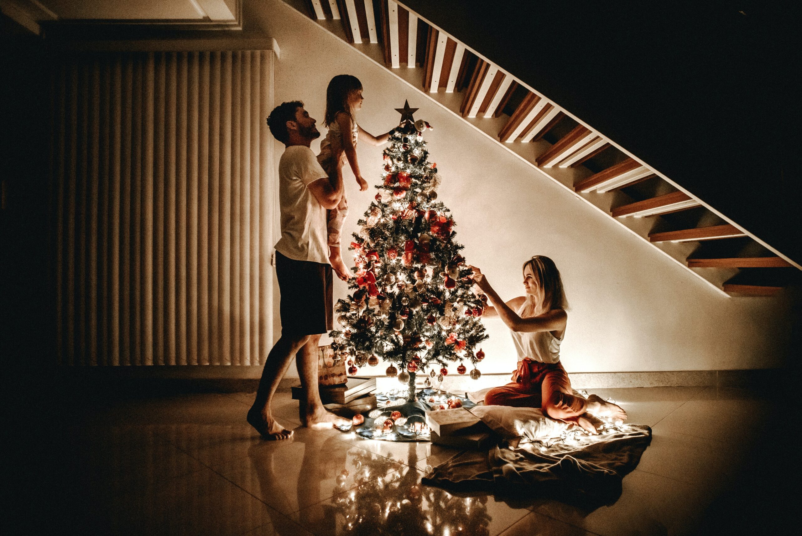 silhouette of a family decorating a christmas tree for a family christmas