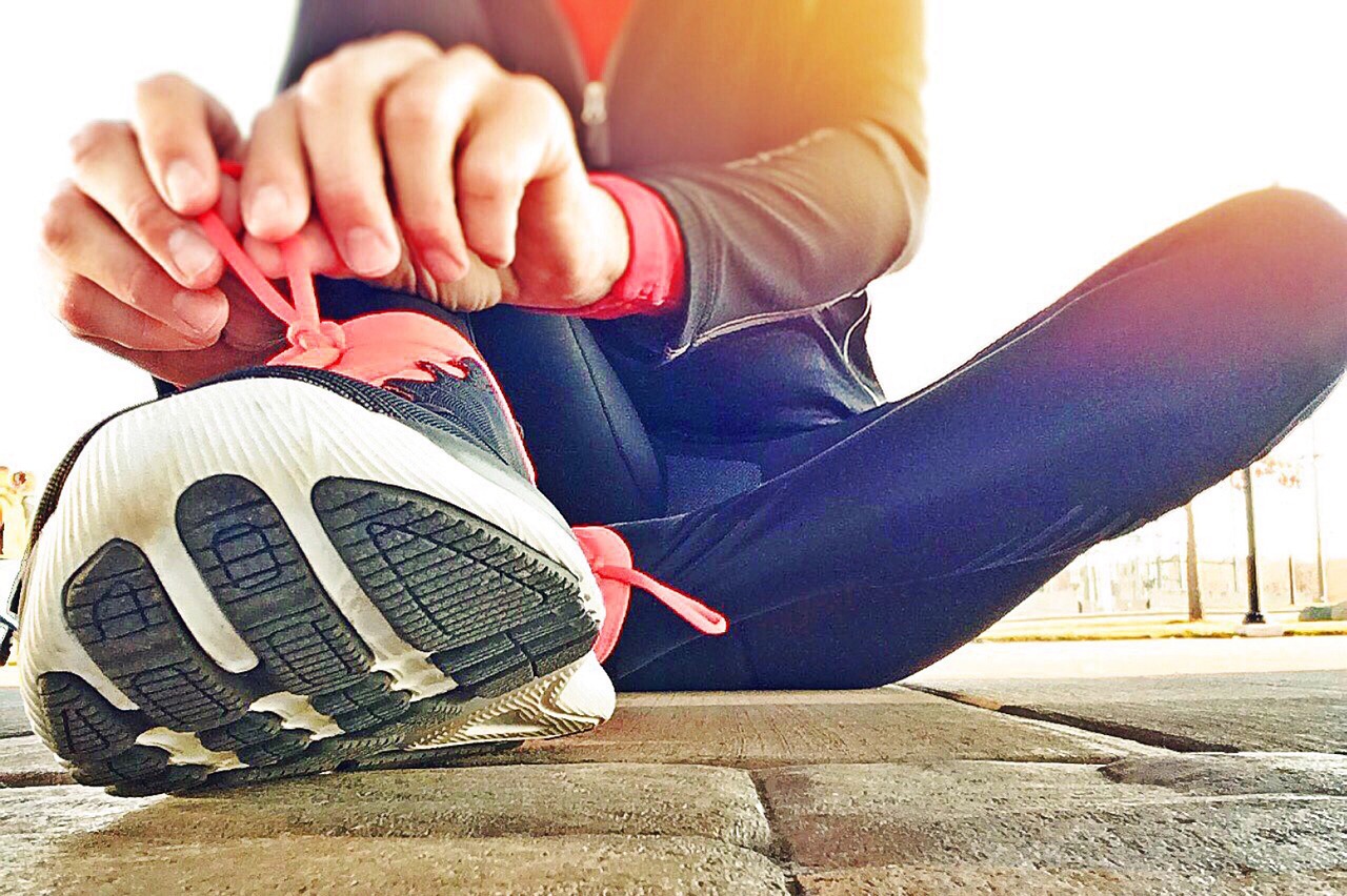 close up of a runners shoes and a person tying laces