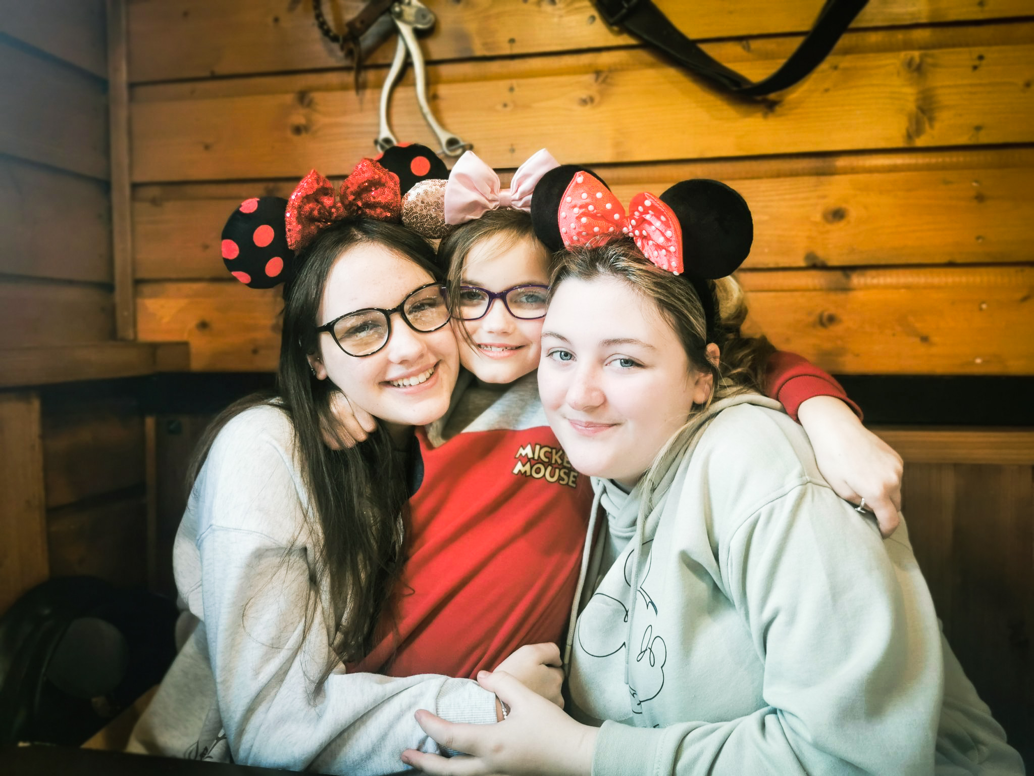 three young girls in a cowboy setting wearing mickey mouse ears