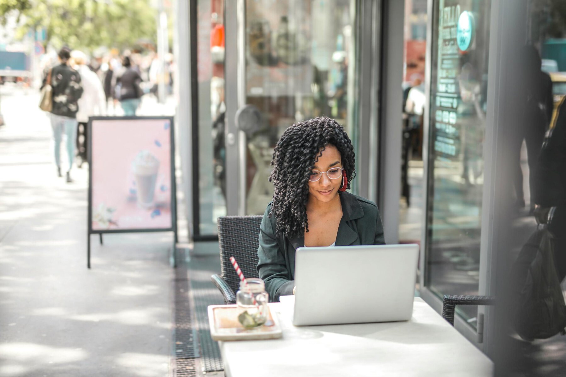 woman sat at a table outside working on a laptop