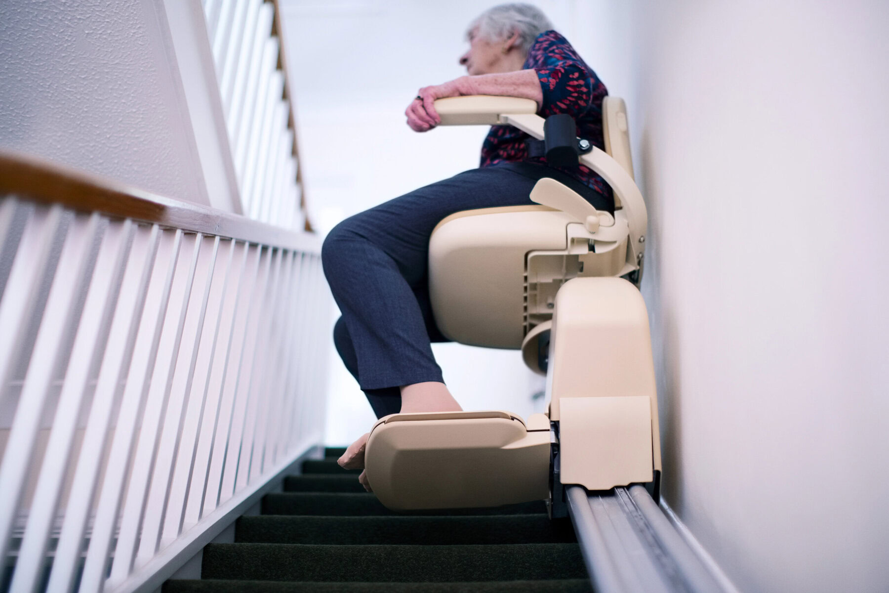 a shot of a woman on a starlift in a home environment movign down the staircase