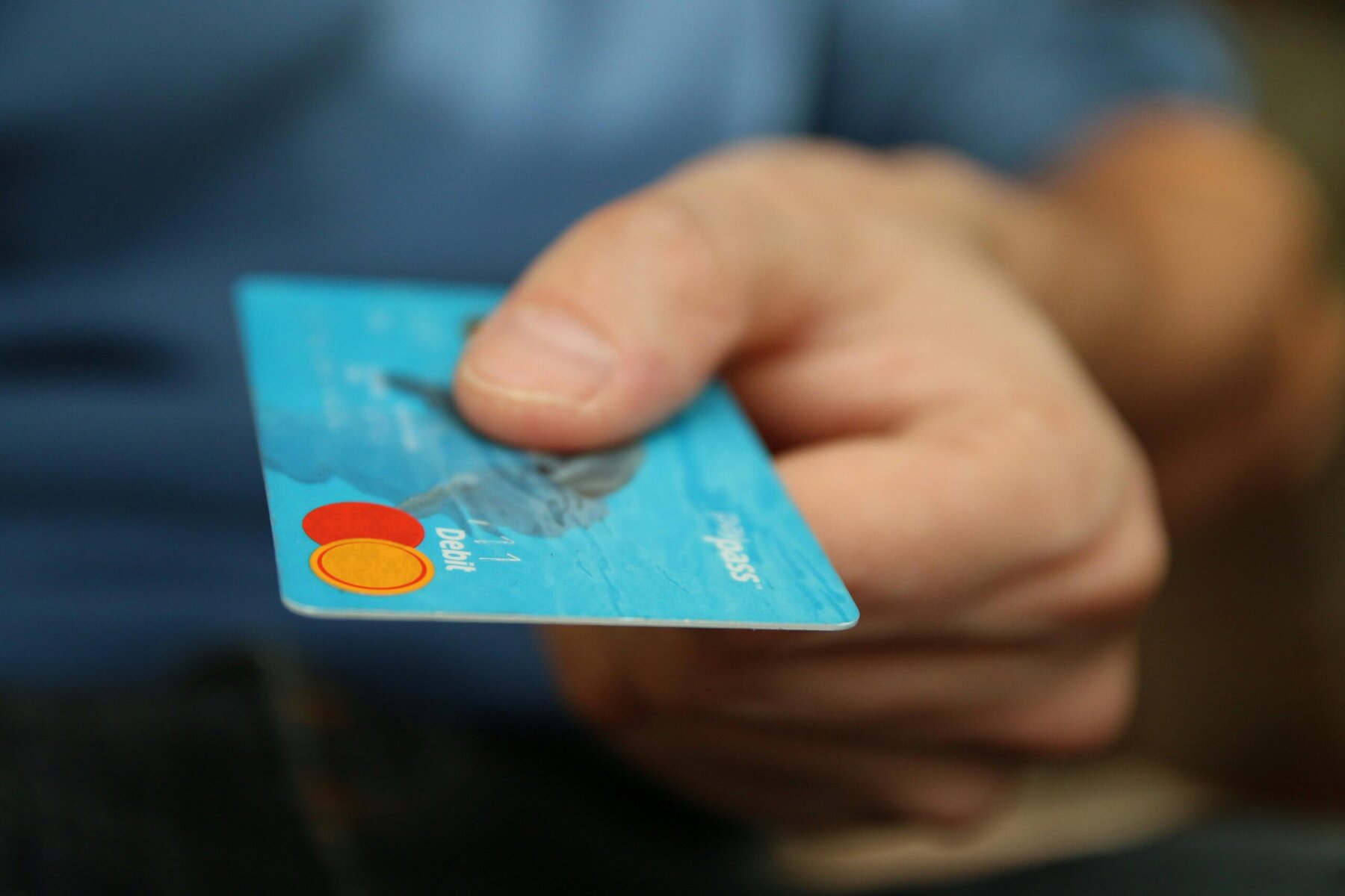 Hand holding a debit card above a table, ready to make a payment.
