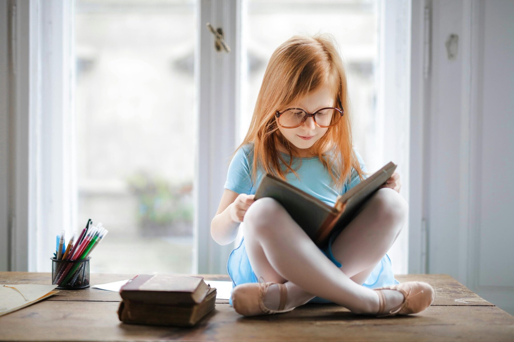 Young girl reading a book while sitting on the floor at home, focused and relaxed.