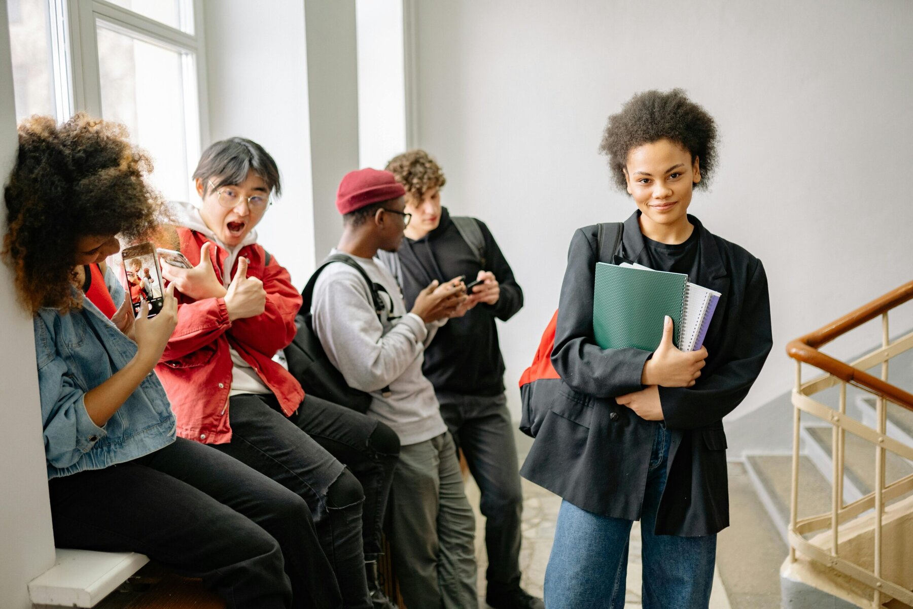 Sixth form students sitting on stairs with books and bags, socialising between classes.