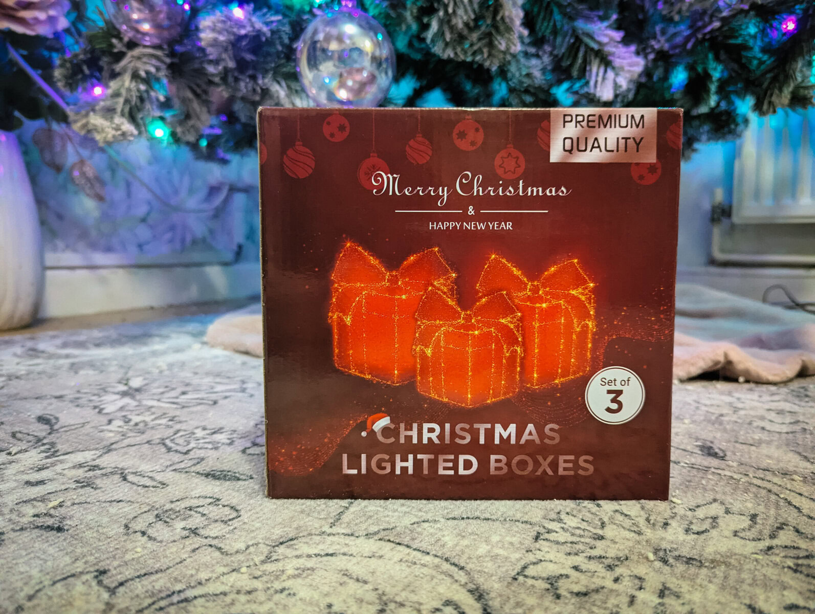 a red box under a christmas teee with the Qunti light-up present boxes in white inside
