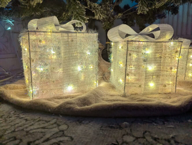 a front view of the white quntis light-up pesent boxes switched on with the lgihts static on a pink christmas tee skirt