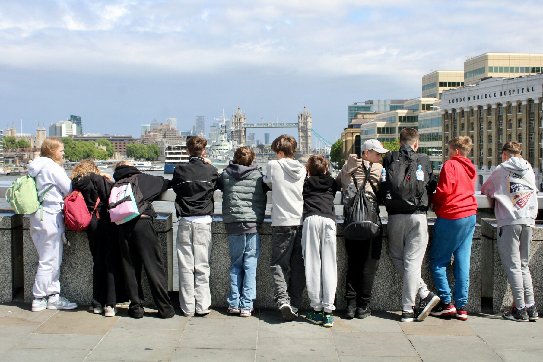 Group of teenagers wearing backpacks overlooking Tower Bridge and the River Thames in London