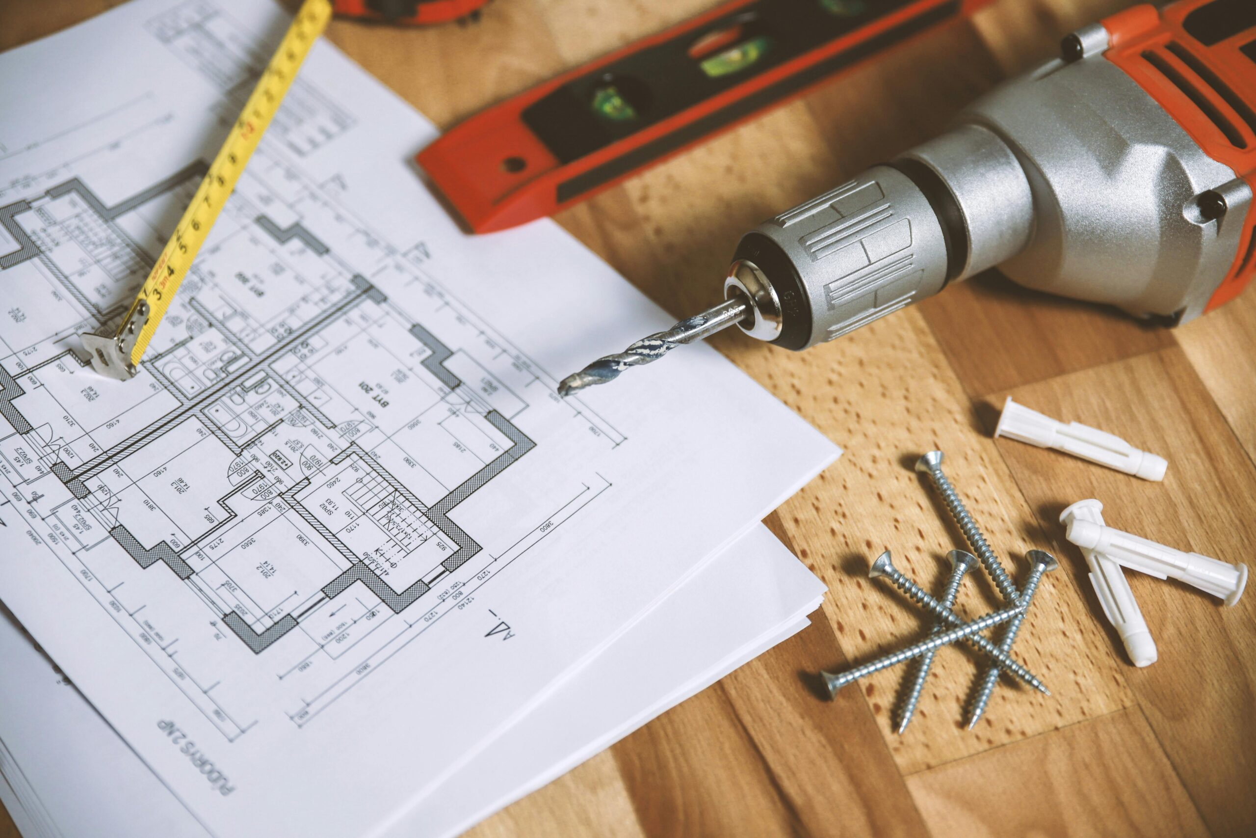 Architectural floor plan on a wooden table with tools and hardware