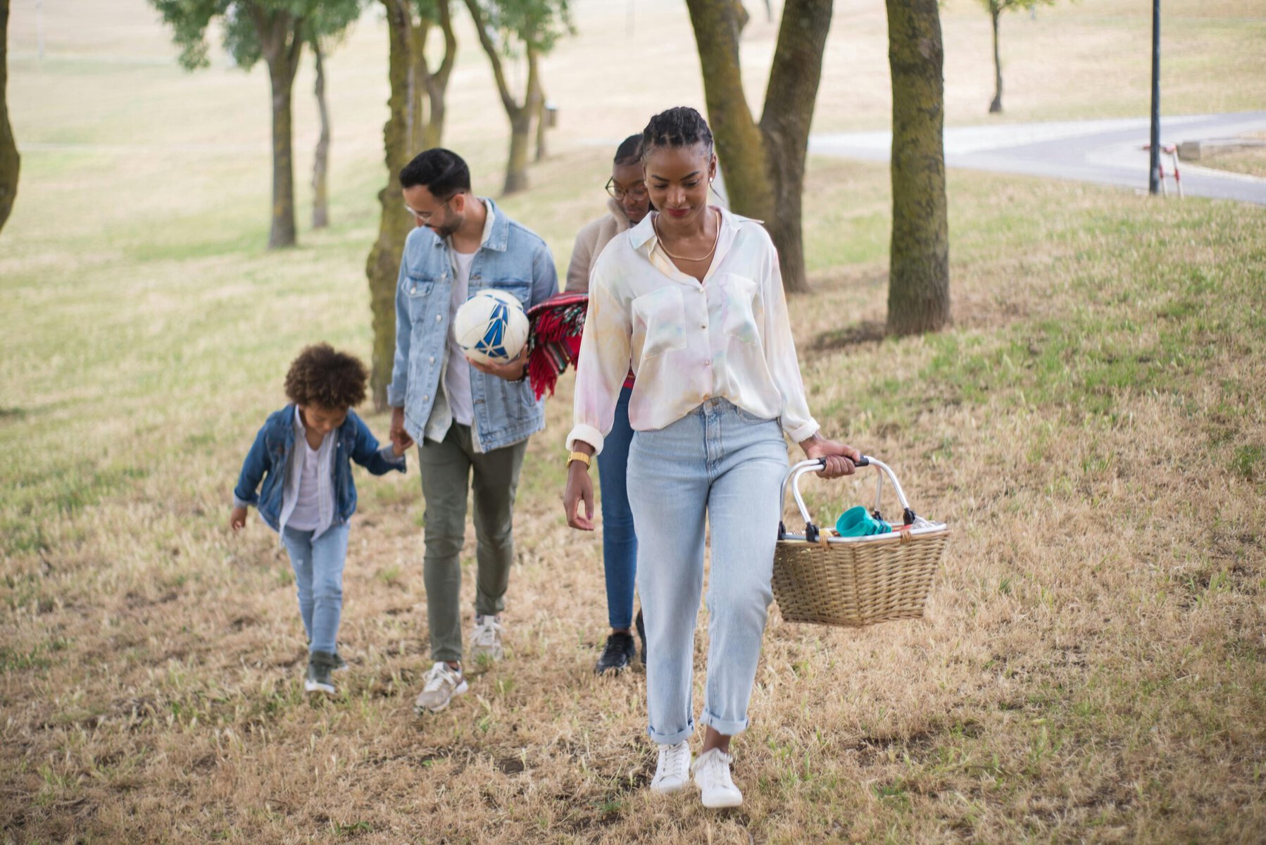 Family walking across green grass in a park on a sunny day