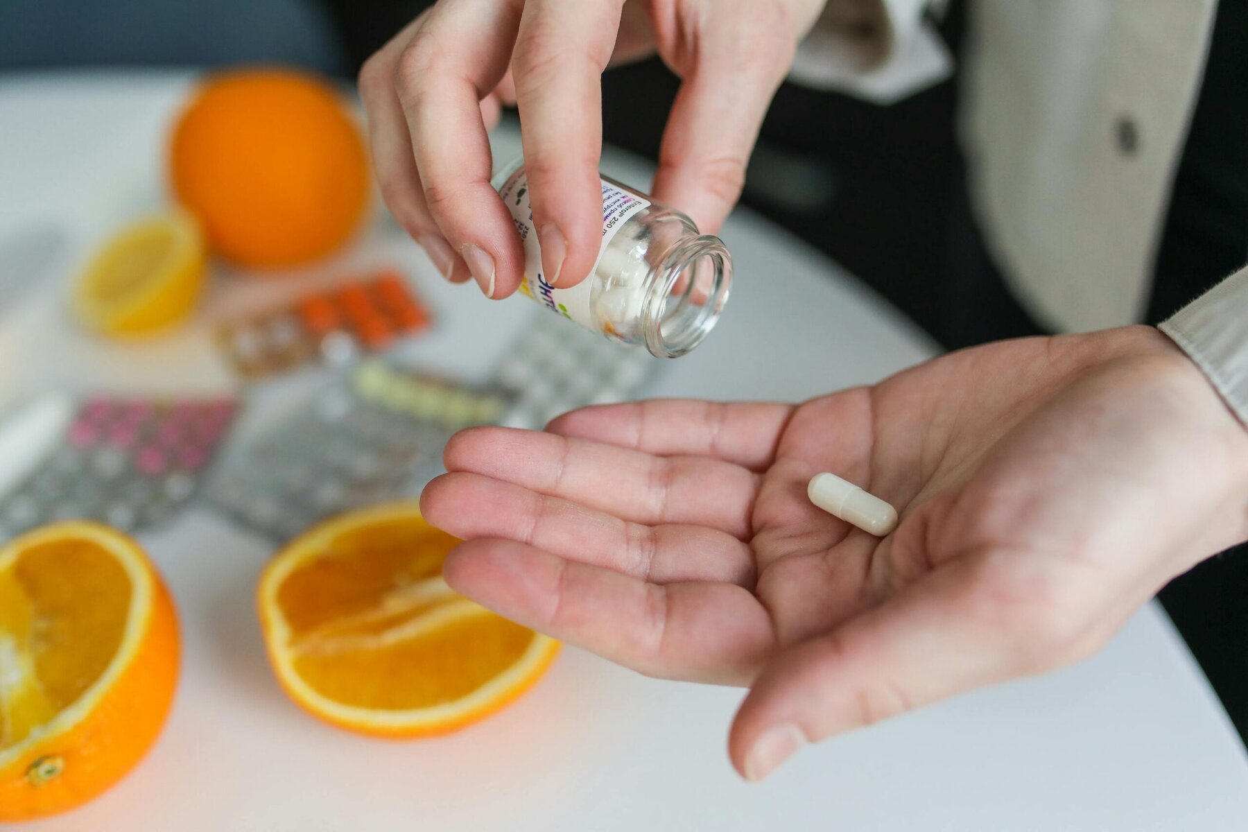 Person holding a glass of water while taking a pill at home.