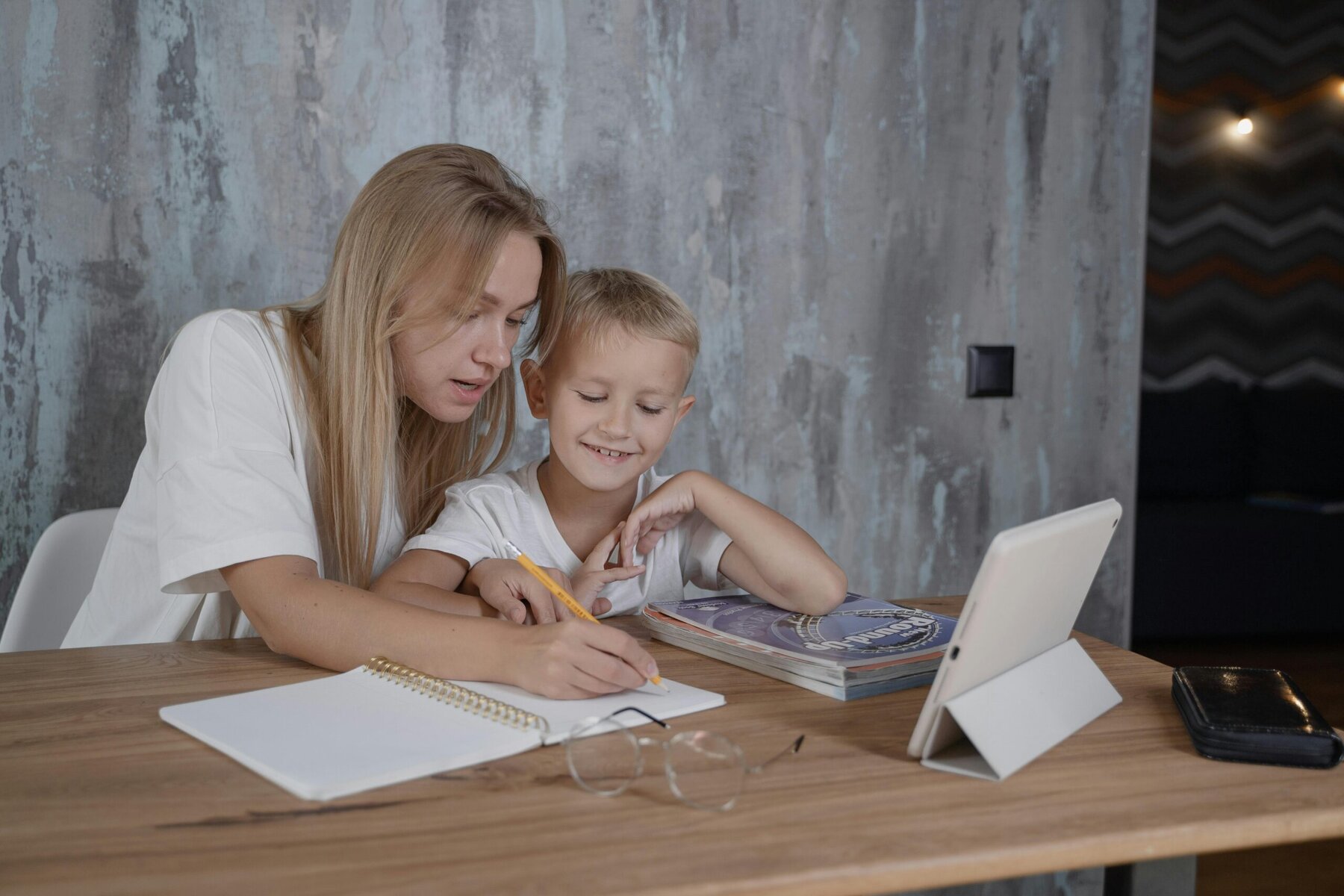 Woman writing in a notebook beside a young boy