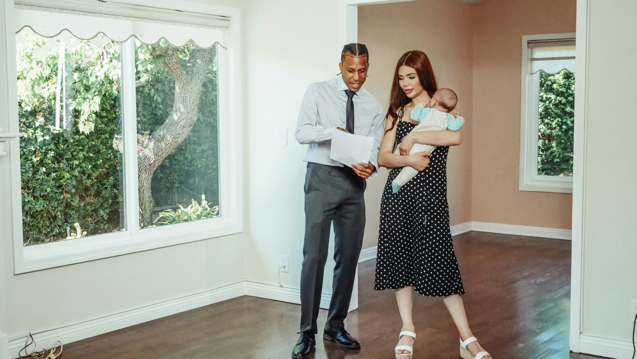 A couple discussing details with a real estate agent during a home tour indoors