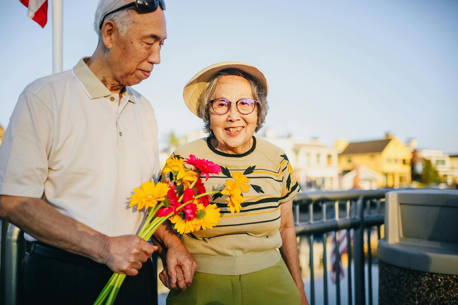 Elderly couple holding hands and flowers outdoors, sharing a tender moment of love and togetherness