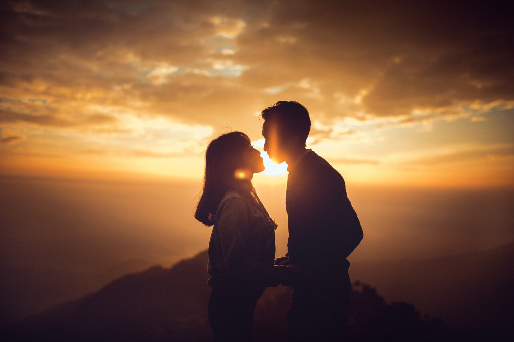 Silhouetted couple standing together at sunset in a mountain landscape