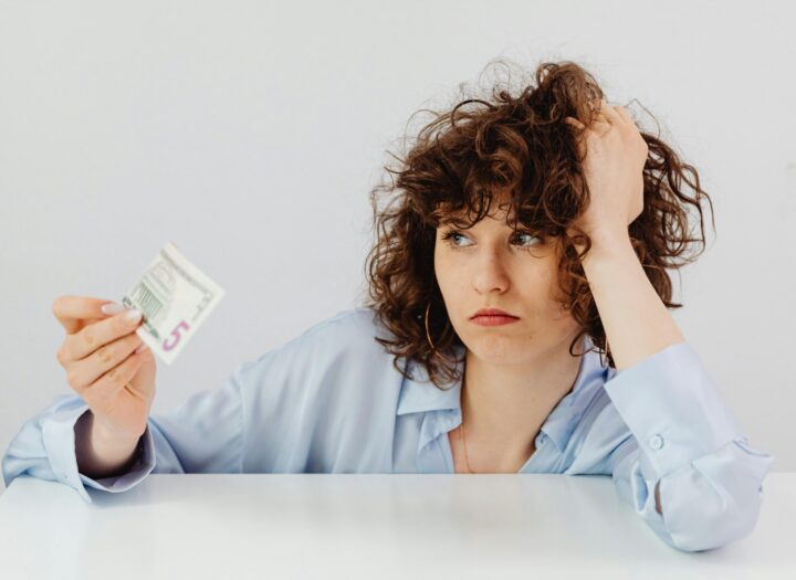 Woman holding paper money while reviewing household finances and budgeting at home.