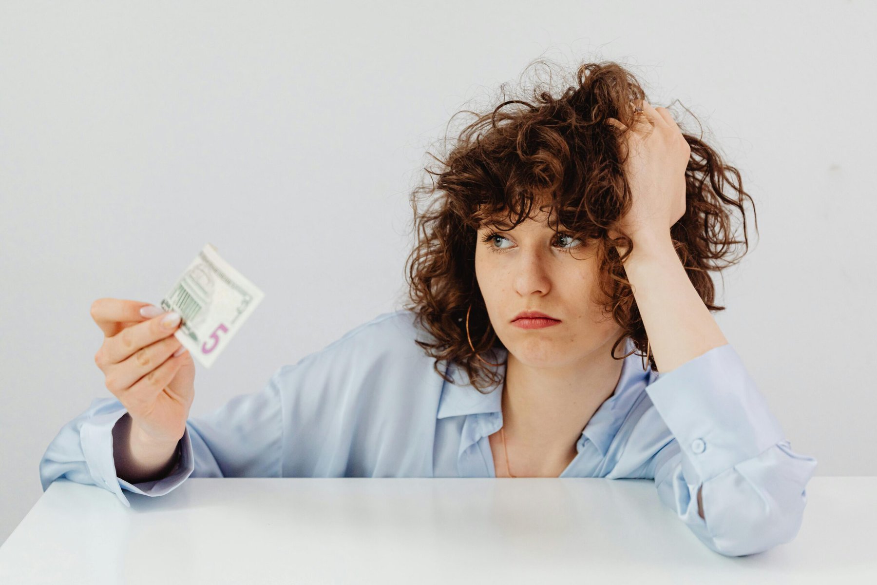Woman holding paper money while reviewing household finances and budgeting at home.