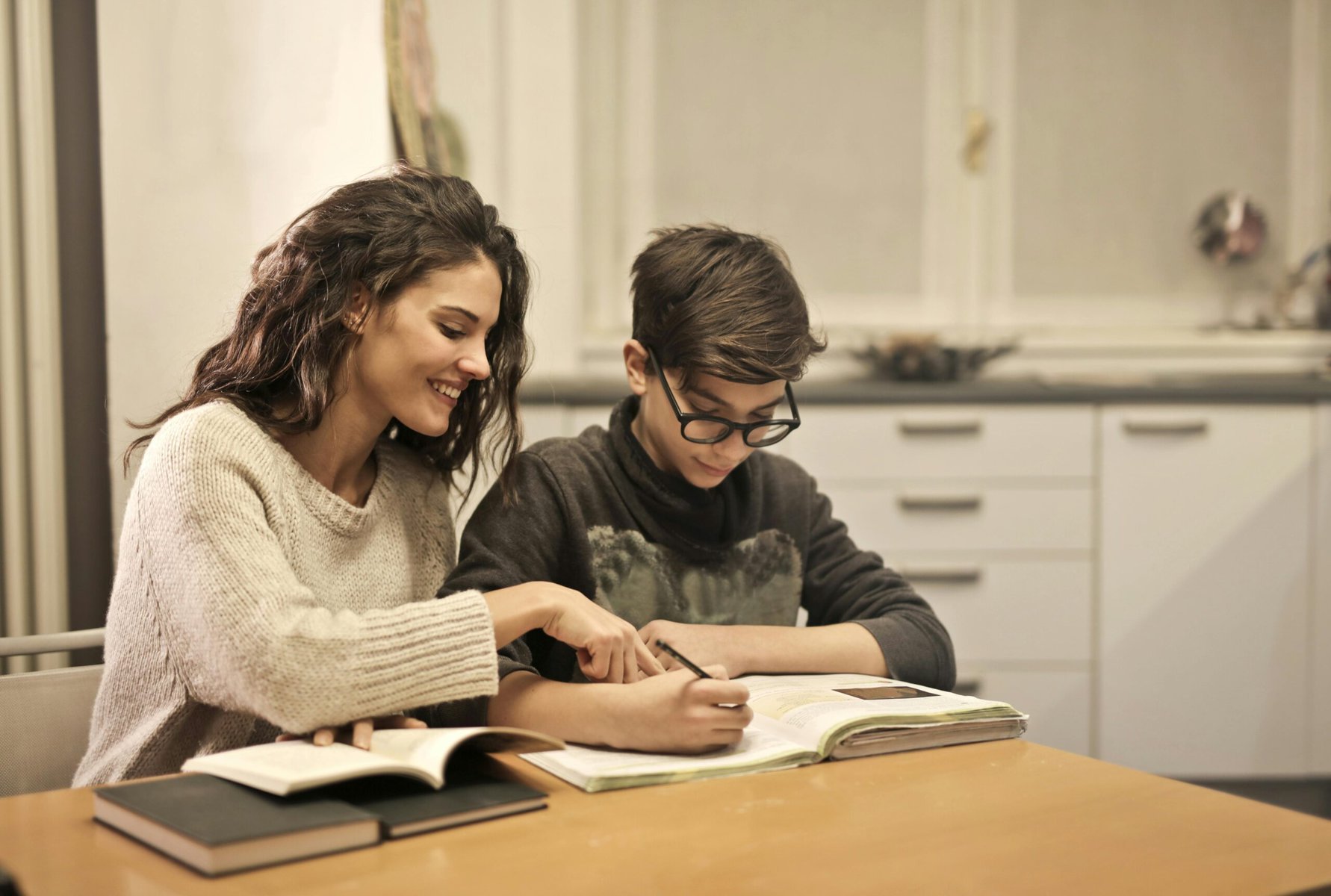 Brother and sister studying together at a table at home with notebooks and school supplies.