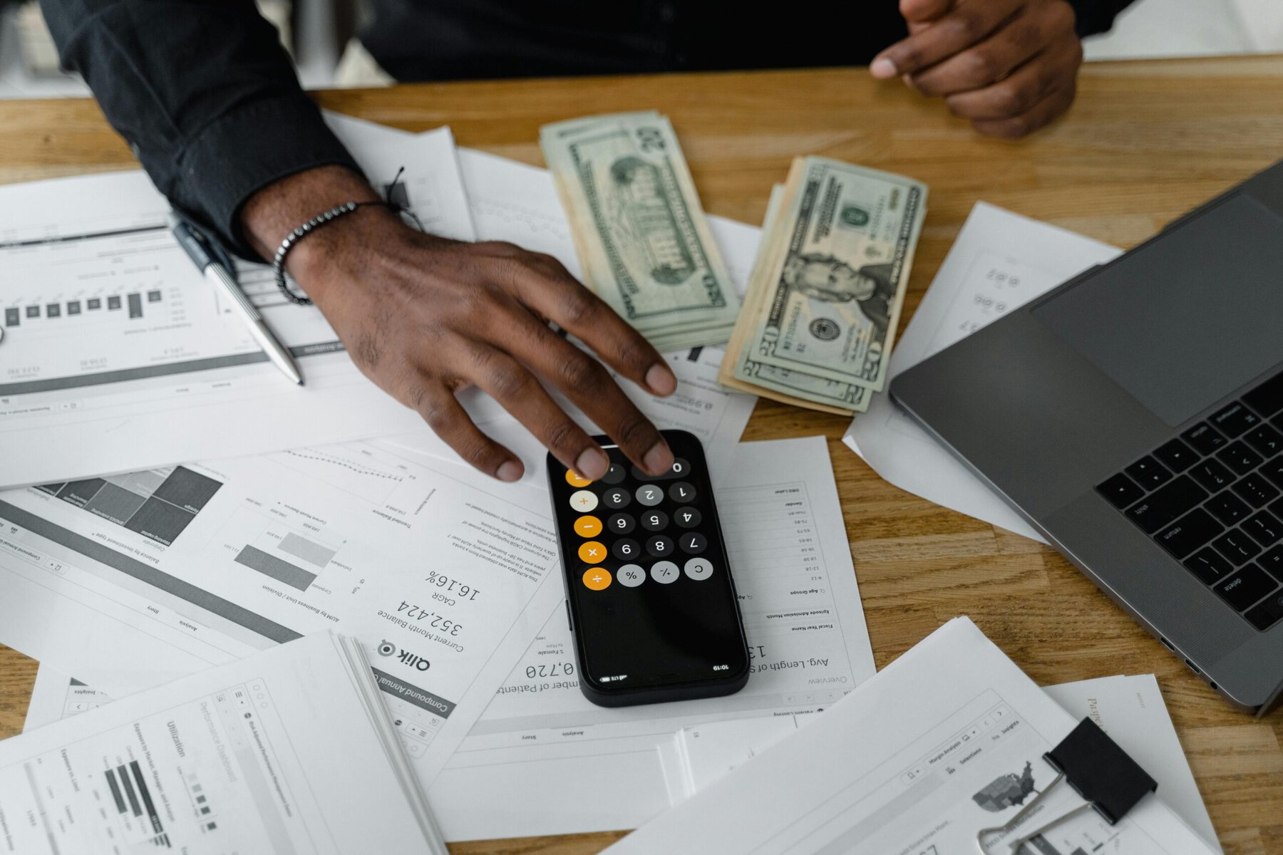 Person using a calculator on a desk with financial documents while reviewing household finances.