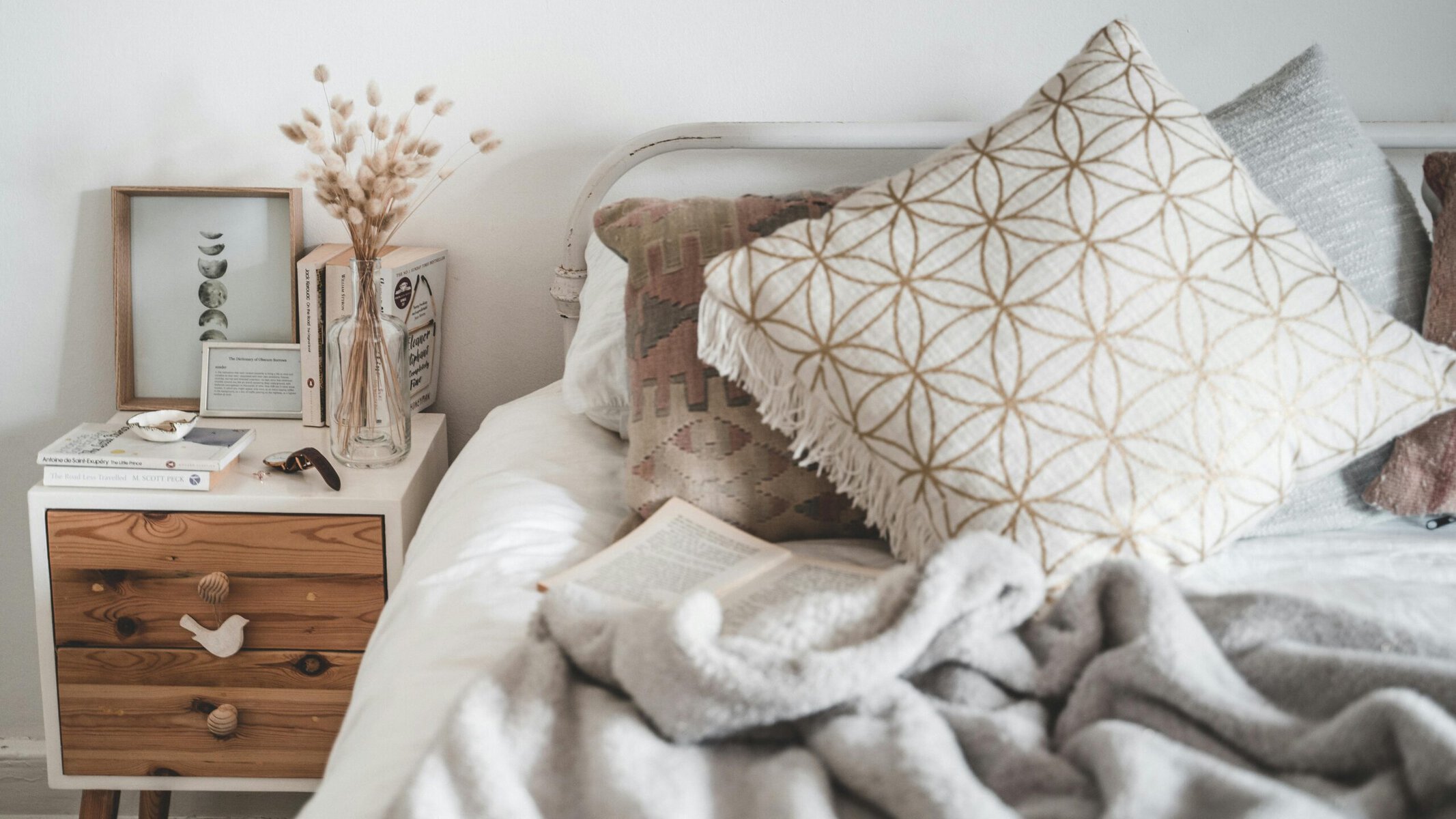 Cosy bedroom with white bedding, layered cushions and warm neutral tones