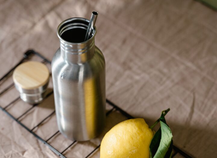 Stainless steel insulated tumbler with straw lid and sliced lemon