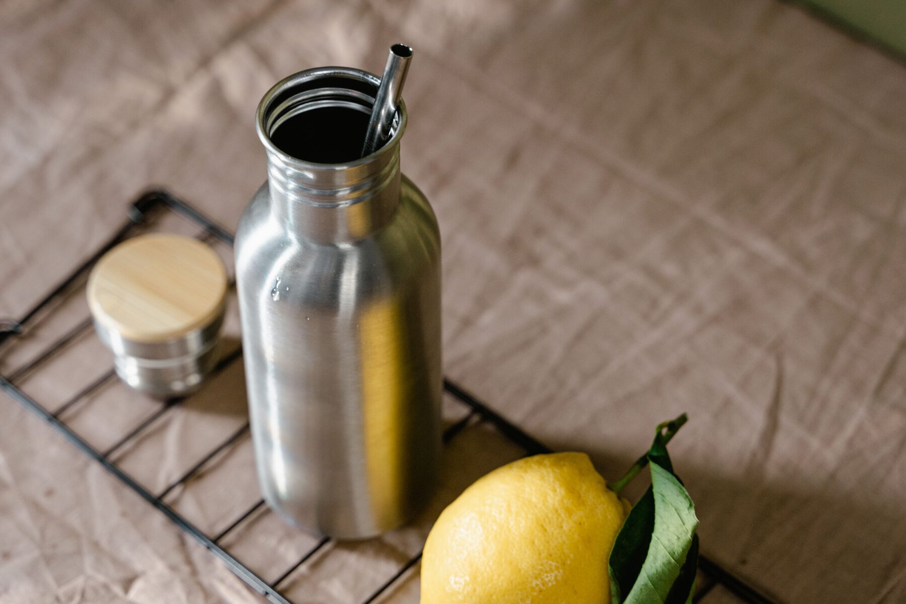 Stainless steel insulated tumbler with straw lid and sliced lemon